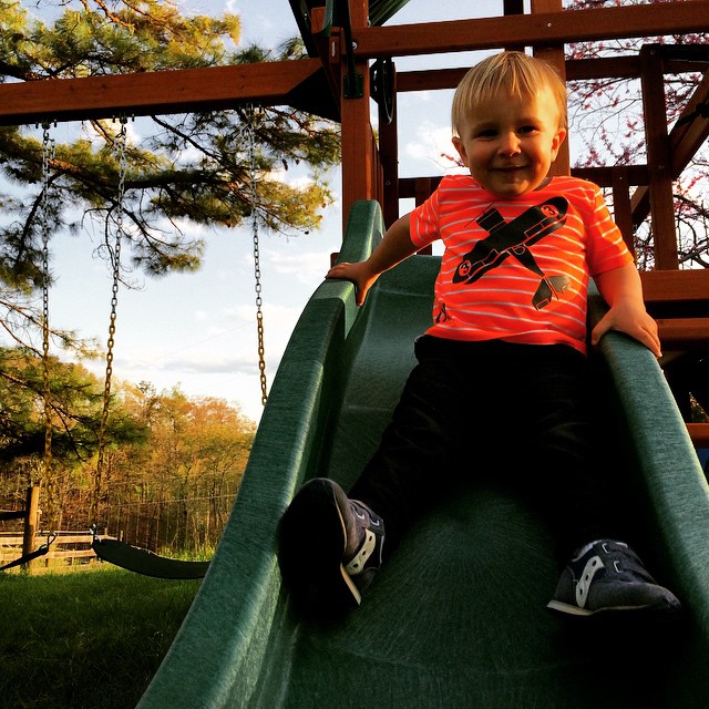 a boy sitting on the edge of a slide