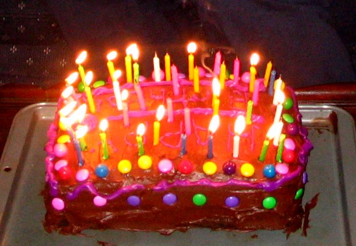 a birthday cake that has candles lit and is decorated