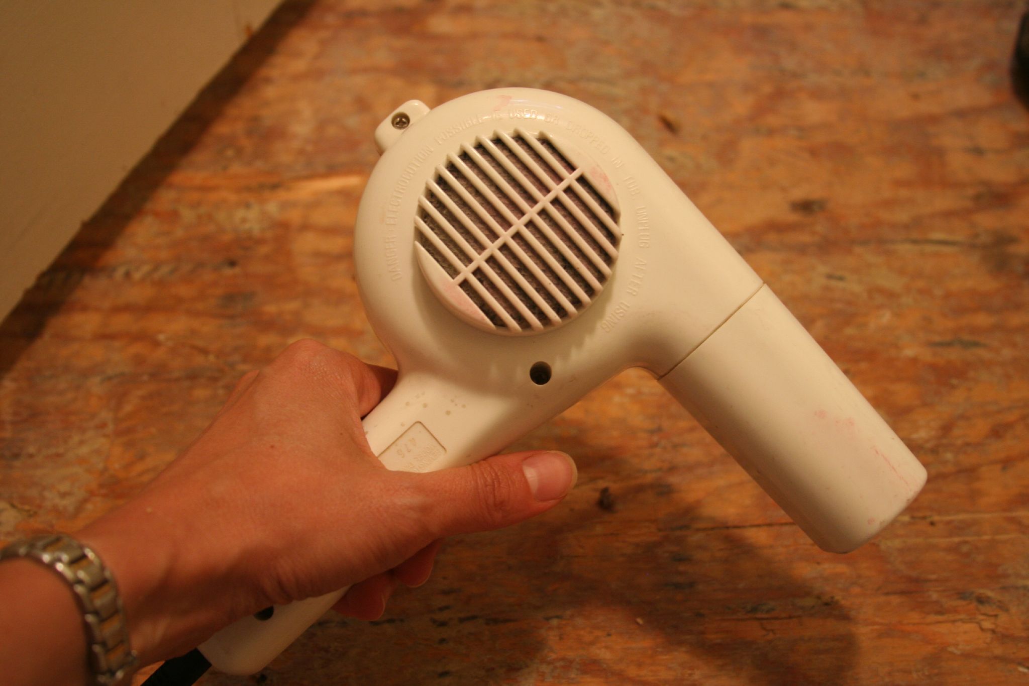 a hand holding a white hair dryer on a table