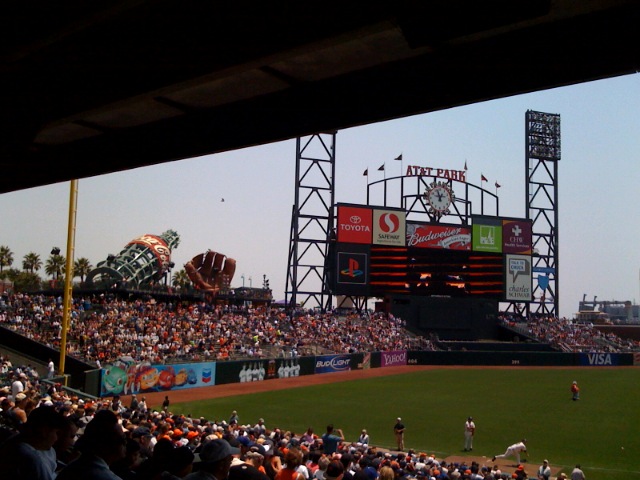 a stadium with fans and the scoreboard and a man getting ready to throw a baseball
