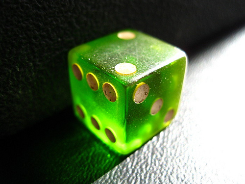a shiny green dice is on a black table
