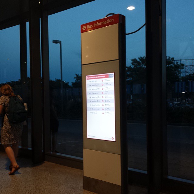 a woman walking through a terminal next to tall windows