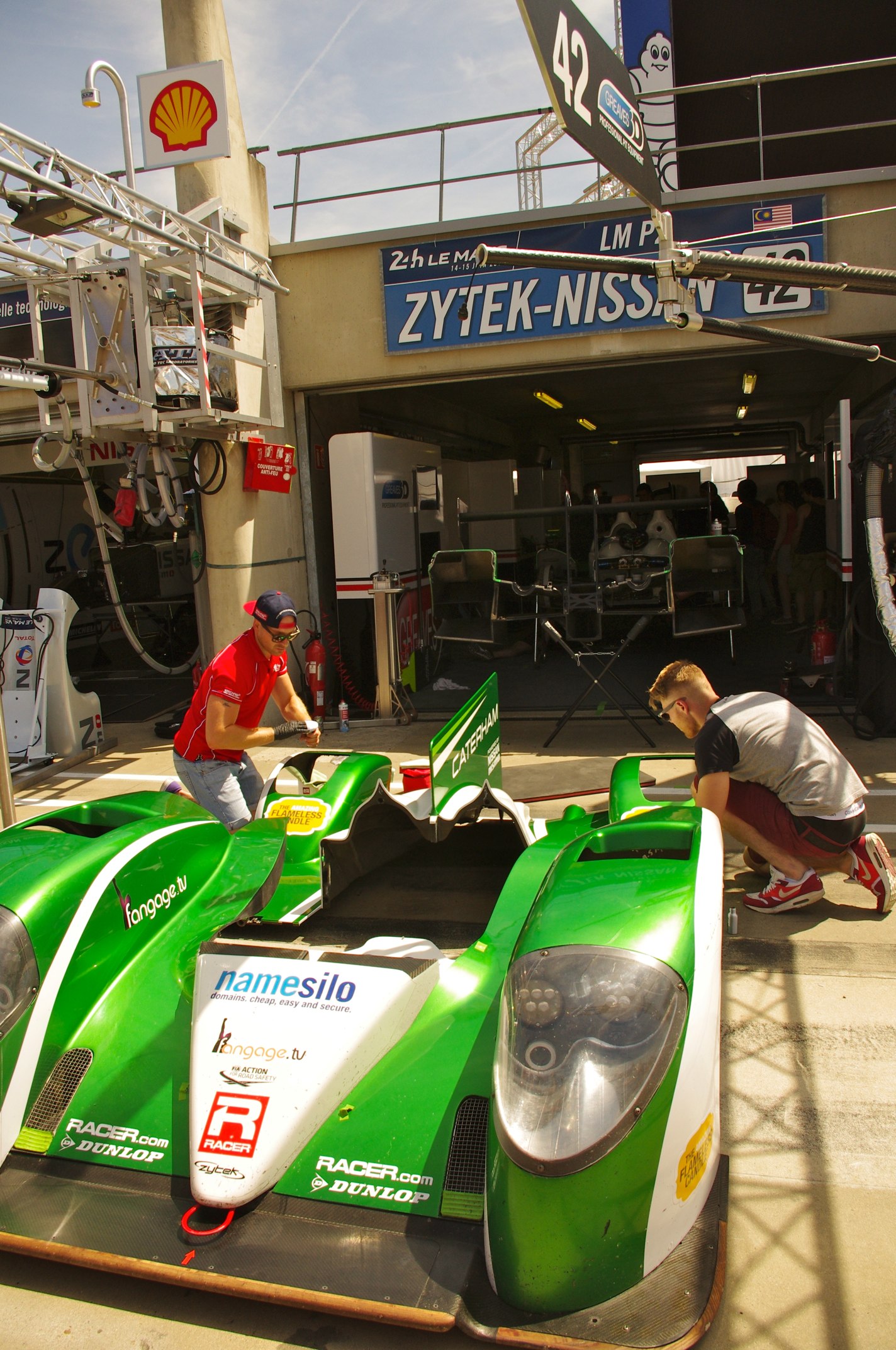a group of men standing around a green race car