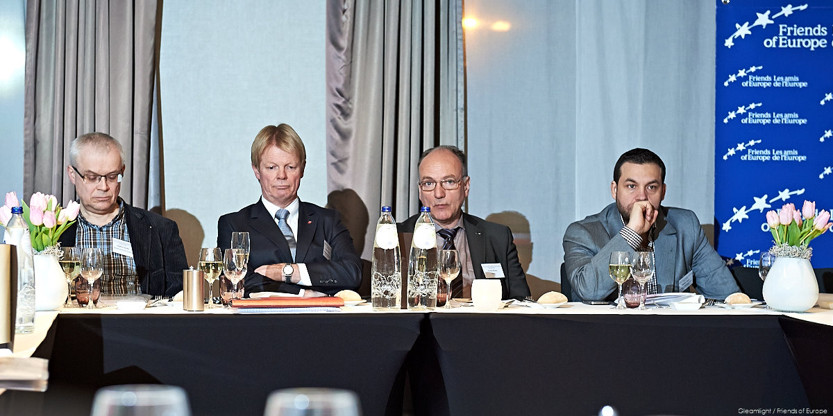 three men are sitting at a table during a press conference