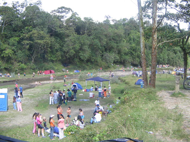 many people standing and sitting around tents near some water