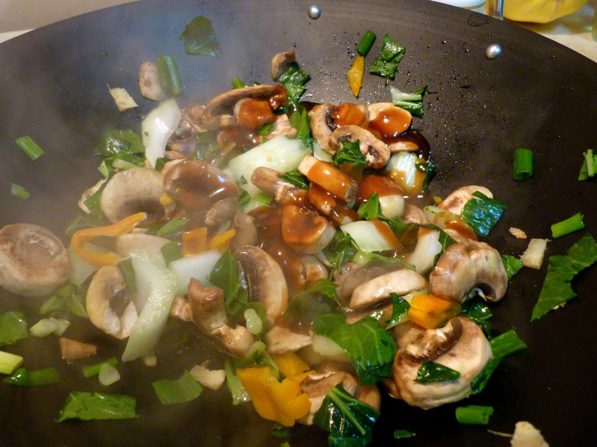 mushrooms, carrots, cucumber and other vegetables being cooked in a pan