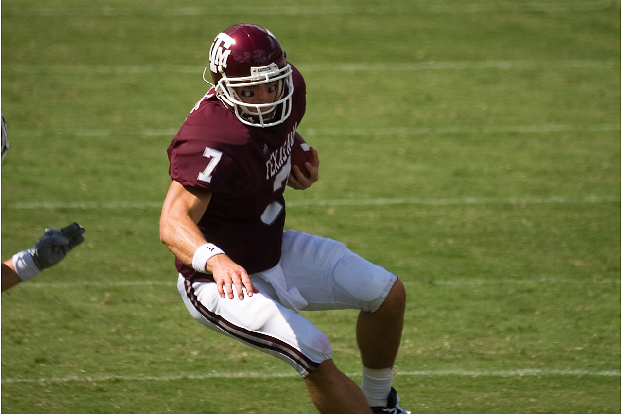 a football player runs in the grass with his helmet and uniform