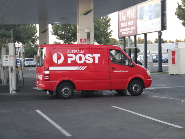 a red van parked at the edge of a gas station