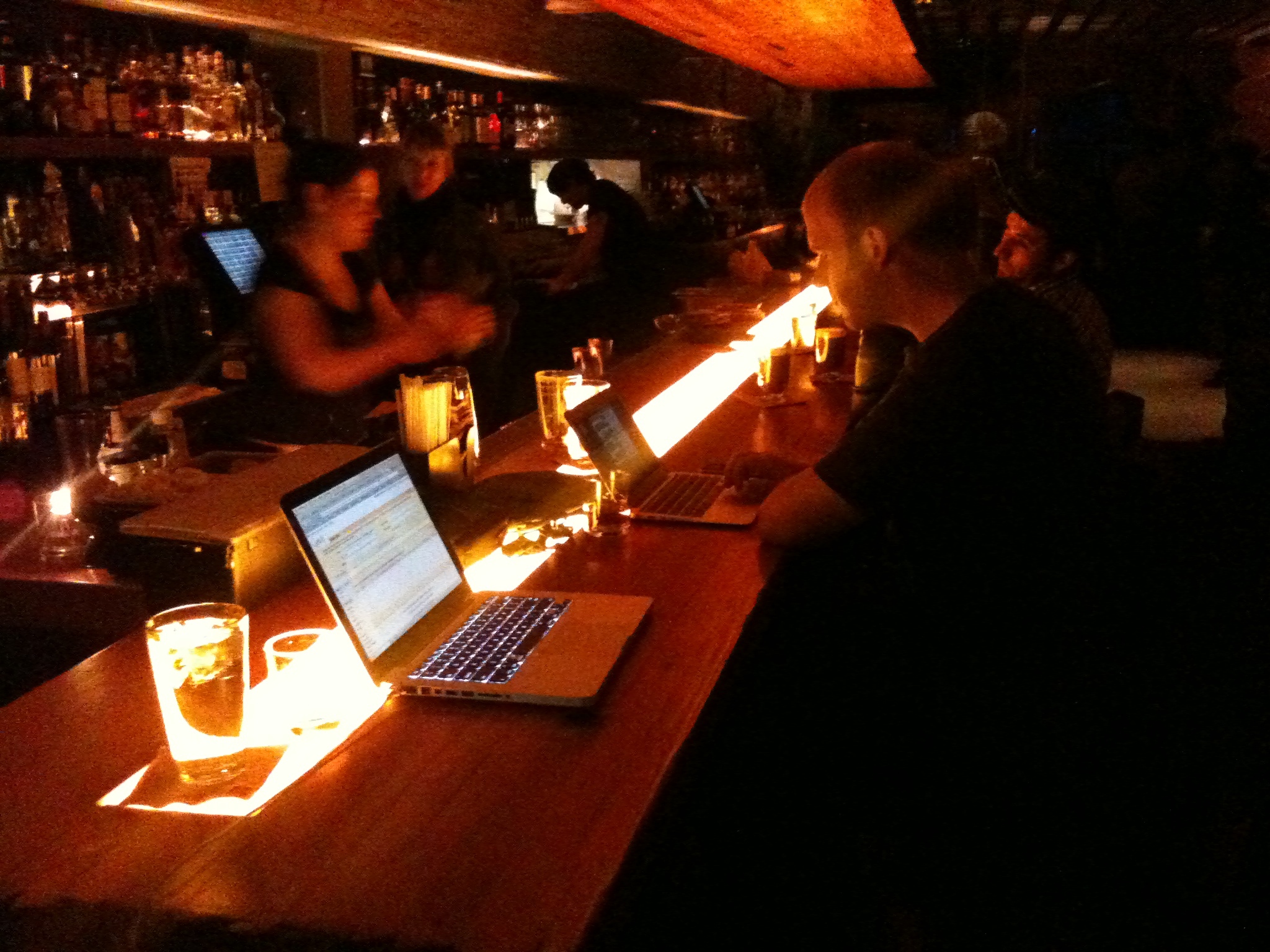 the patrons are sitting in the bar with their laptops