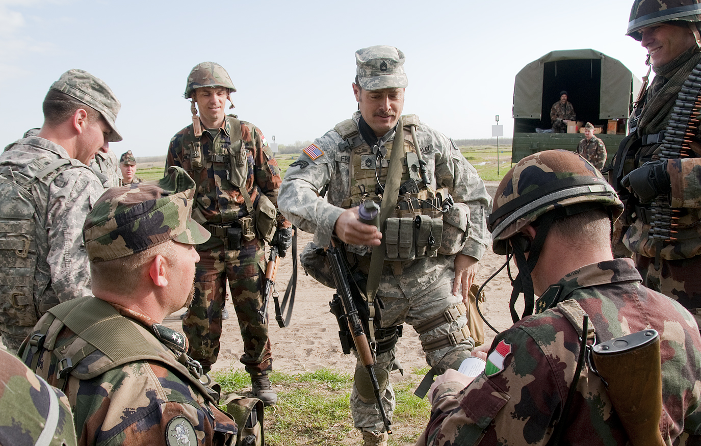 several military men talking while standing in a field