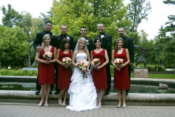 a bride and groom posing with their attendants in front of a fountain