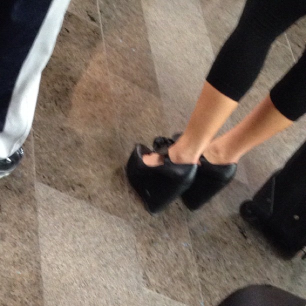 three people standing on a tile floor in shoes