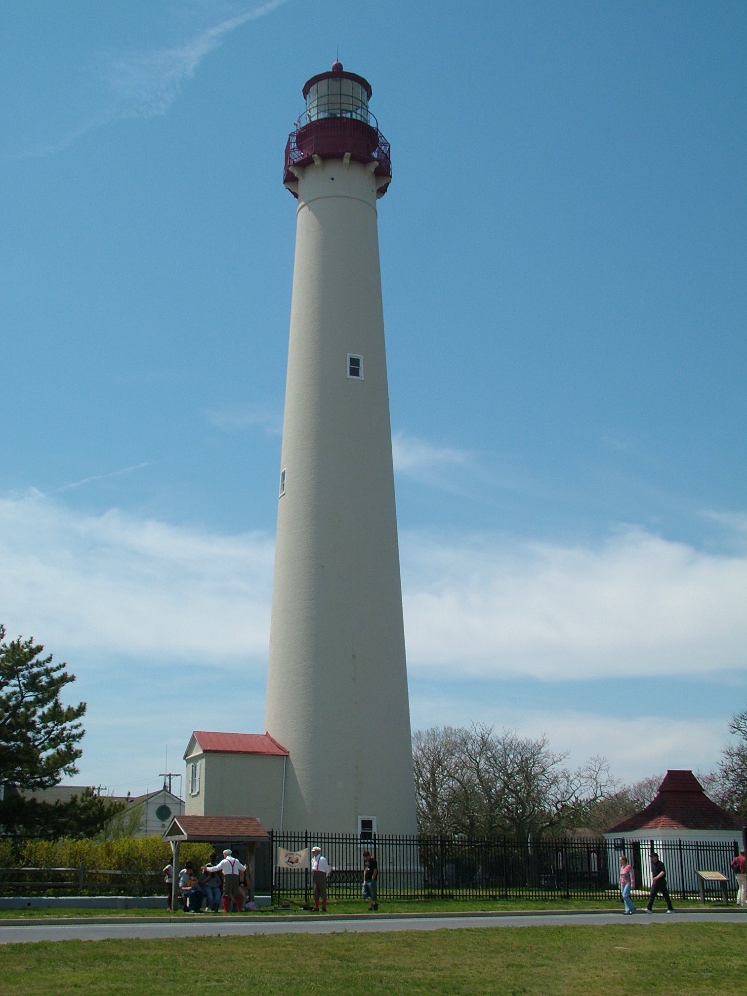 people are in a park near a white and red lighthouse