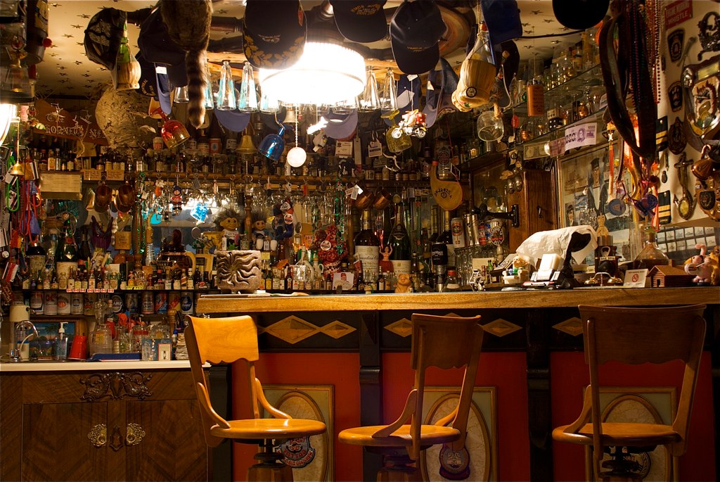 a large set of seats at a bar with many items hanging on the wall