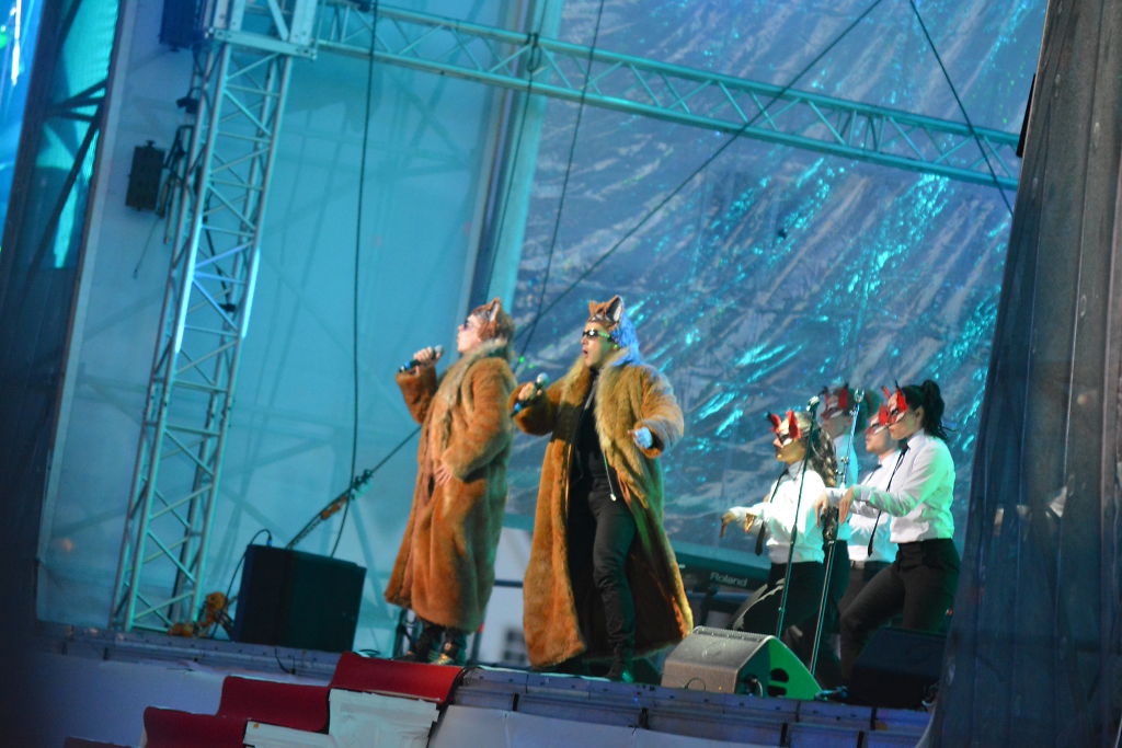 four people in costumes on stage during a concert