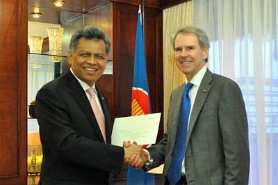 two men shaking hands and a flag in the background