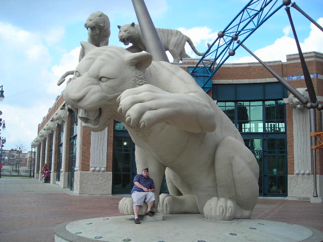 a man sits next to a statue of a cat