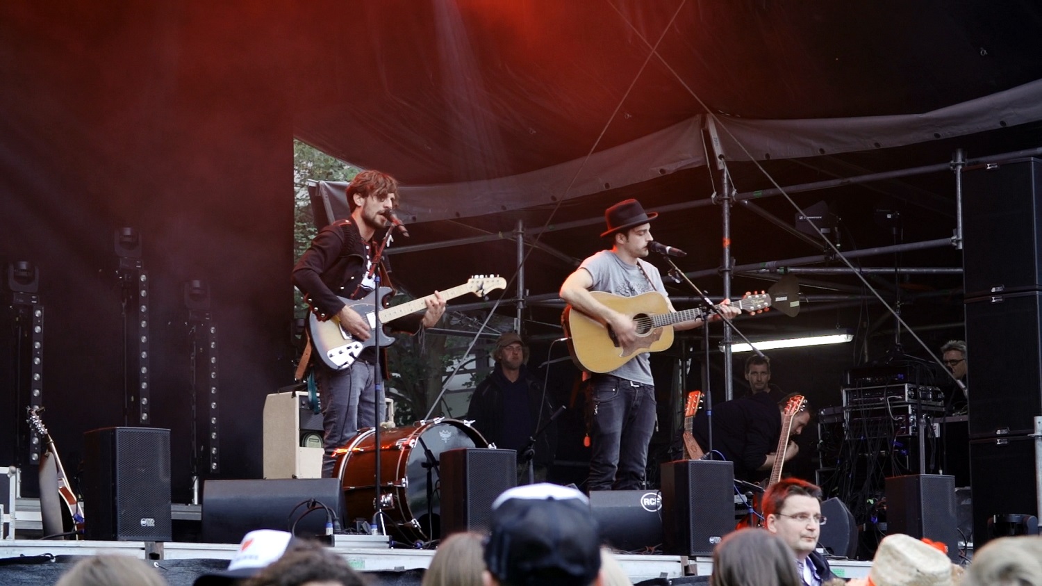 two guys play guitars and sing at an outdoor concert