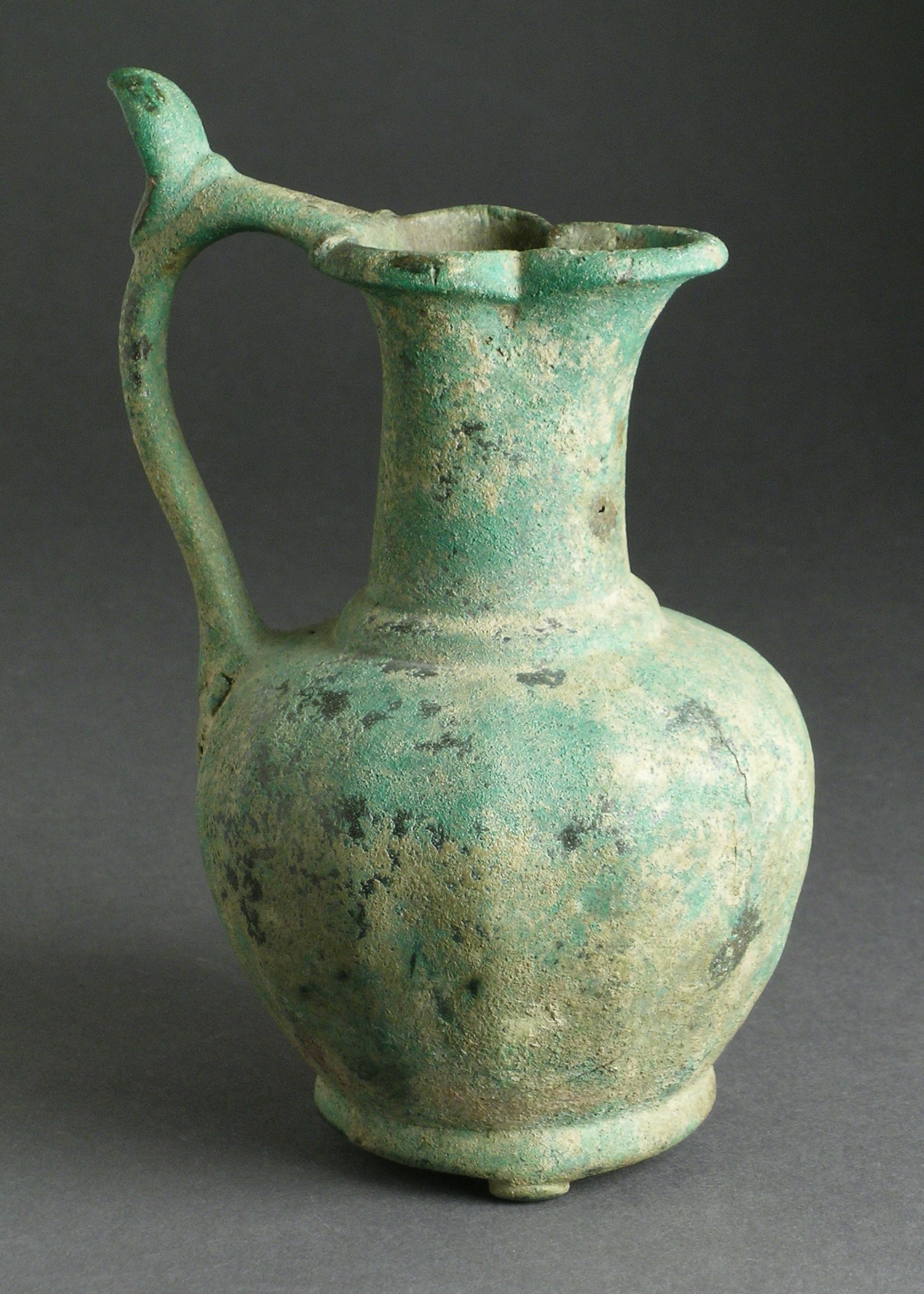 an ancient, blue green vase with a bird motif