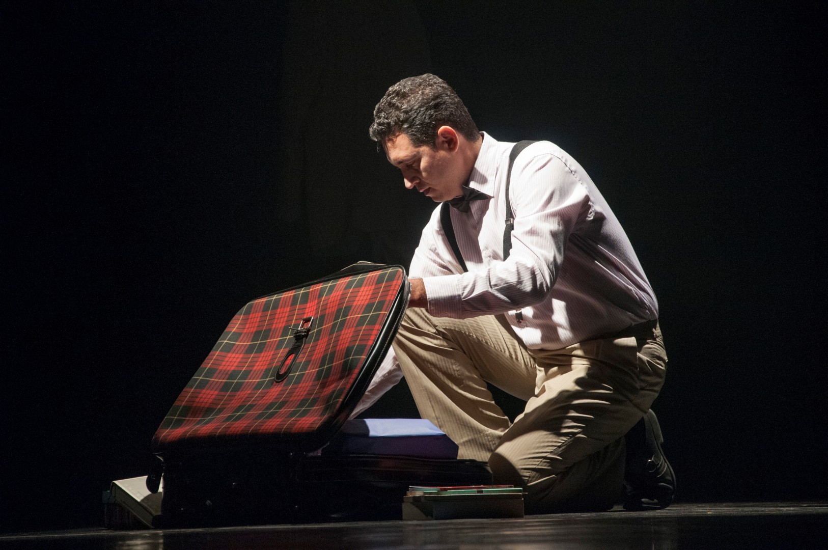 man in tie kneeling on floor near suitcase