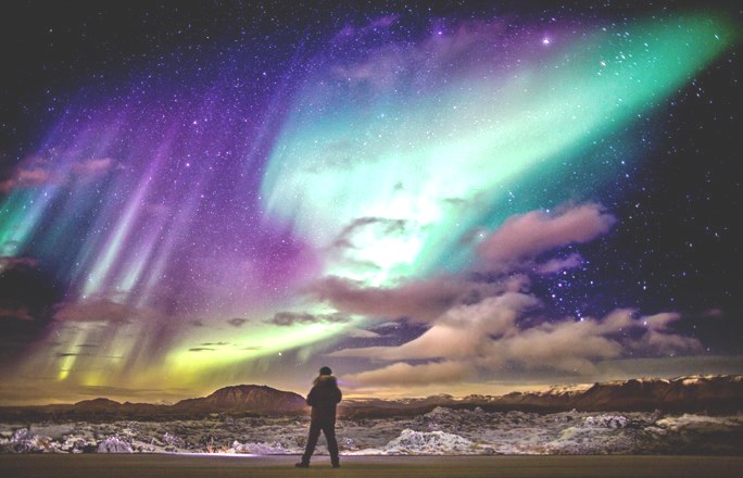 man looking at the night sky with the aurora lights