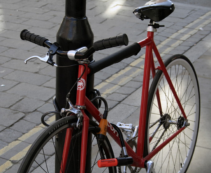 a red bicycle leaning up against a pole
