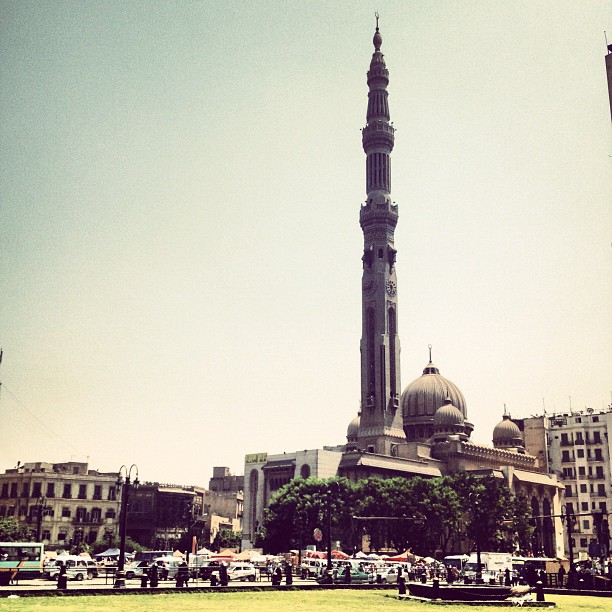 a tall tower with a domed top stands above some cars