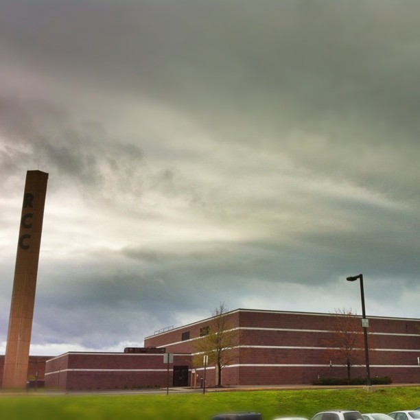 the building is red brick and sits in the foreground as cars are parked in the street