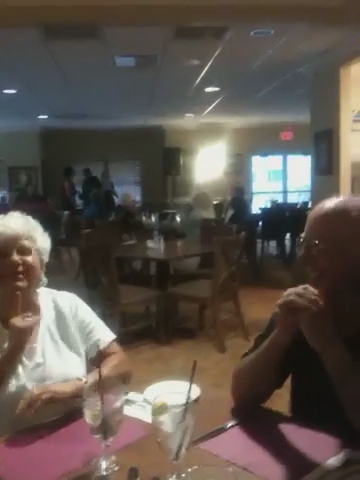two older women sitting at a table having an conversation