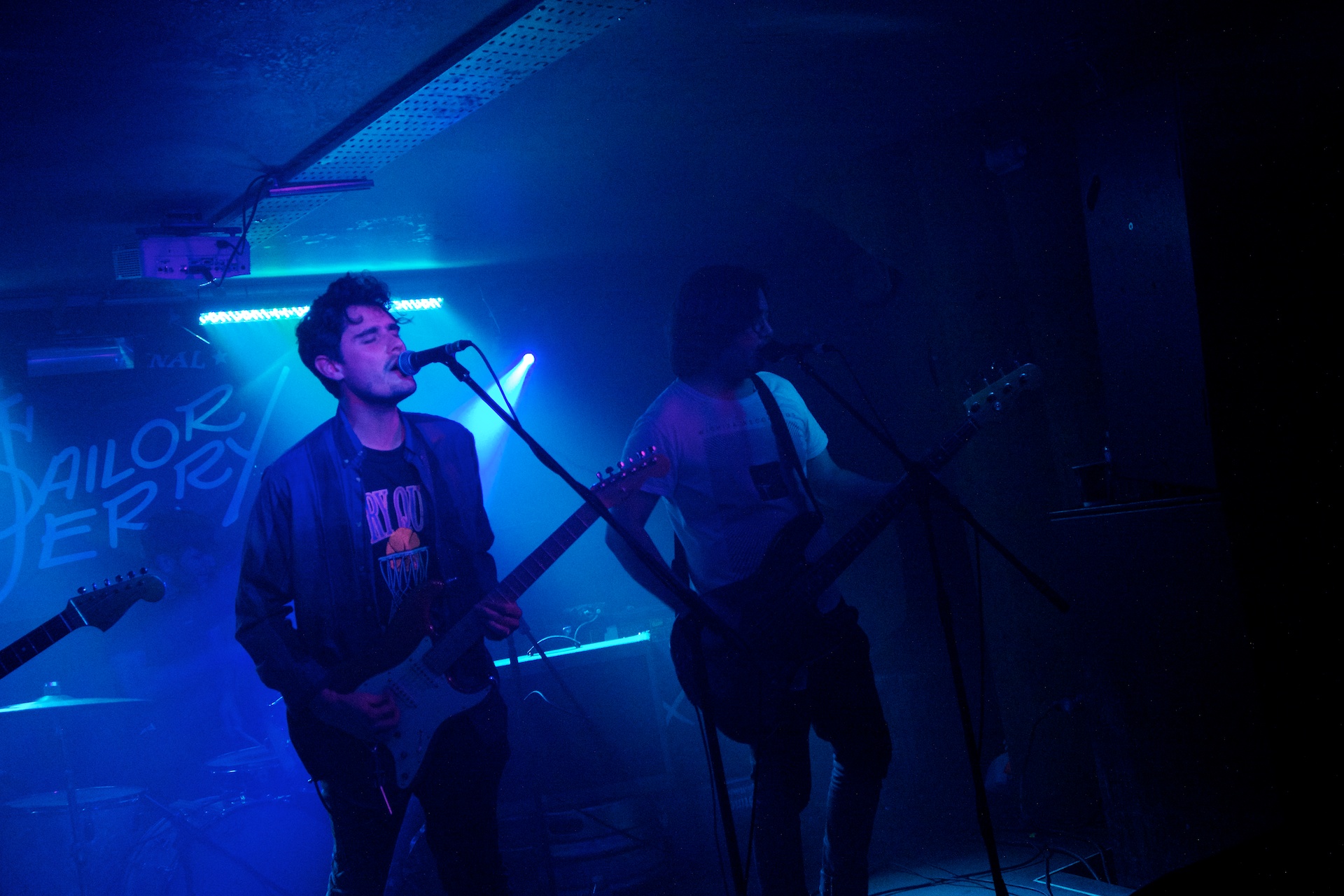 two guys are singing into a microphone while one man is playing the guitar