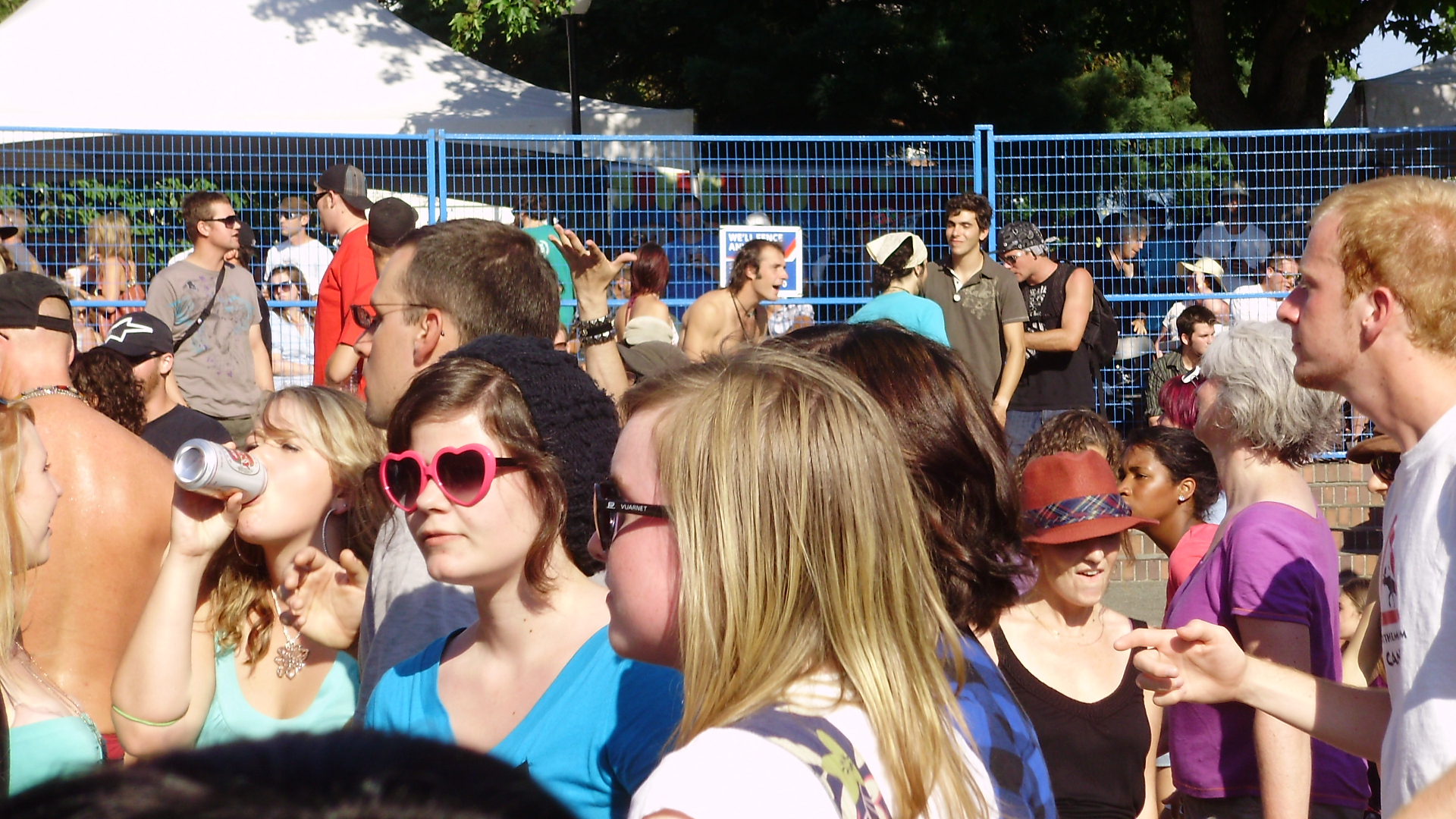 many people are gathered around a white fence