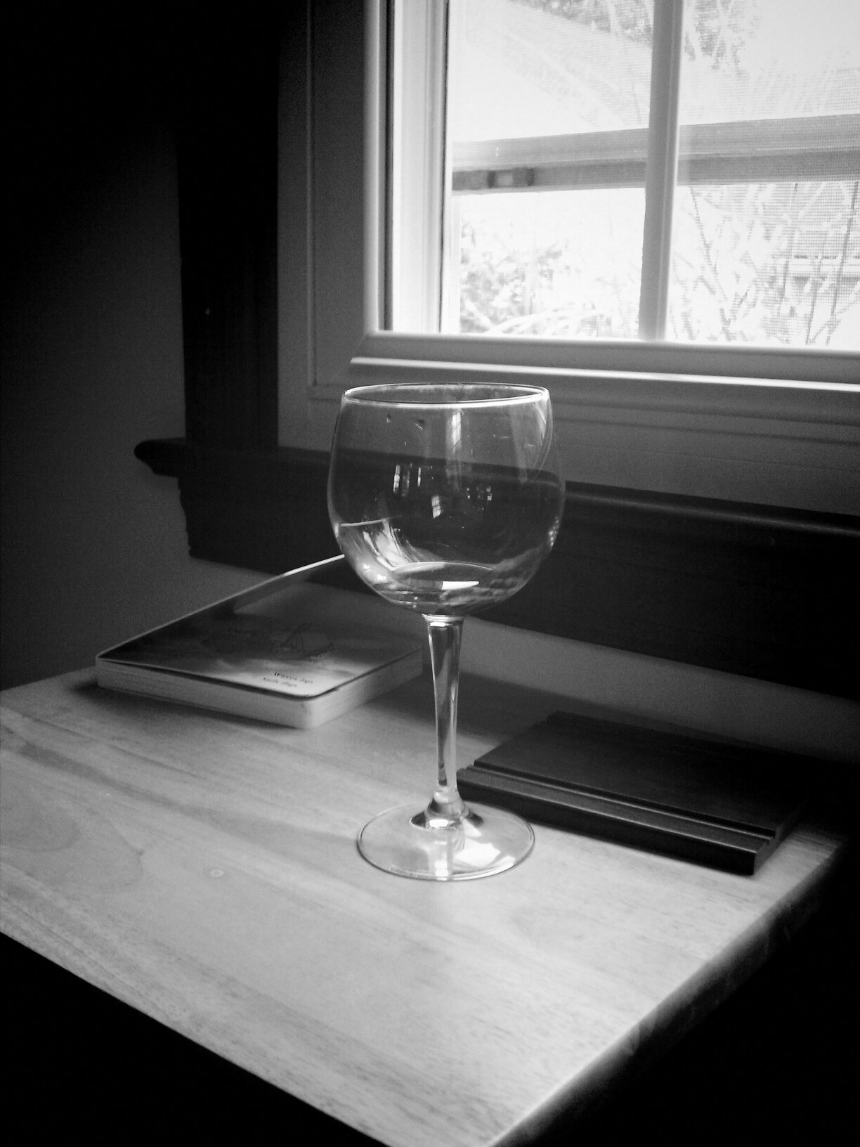 a clear glass of wine sitting in front of a window