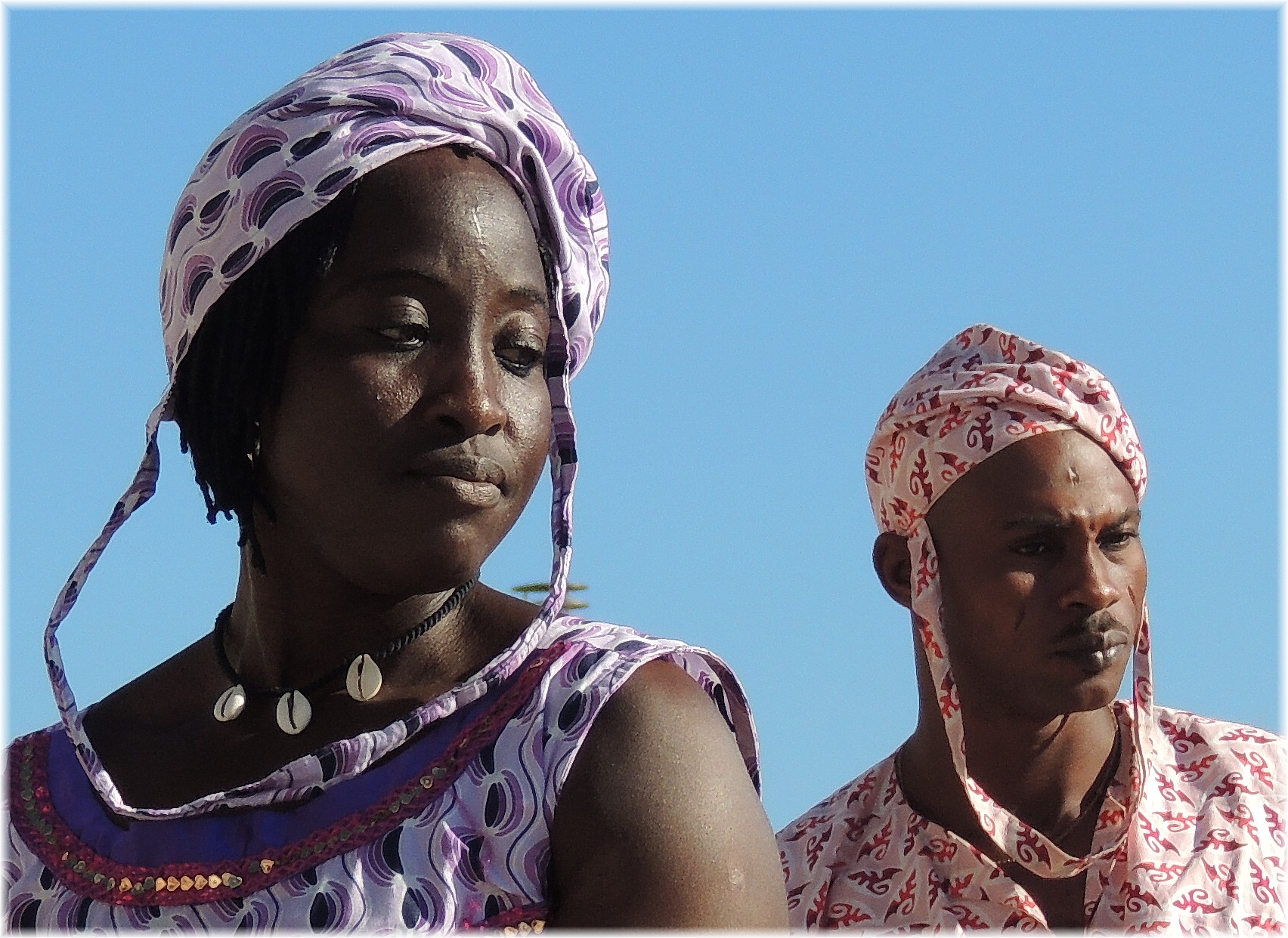 two women in brightly colored patterned clothing are staring off to the left