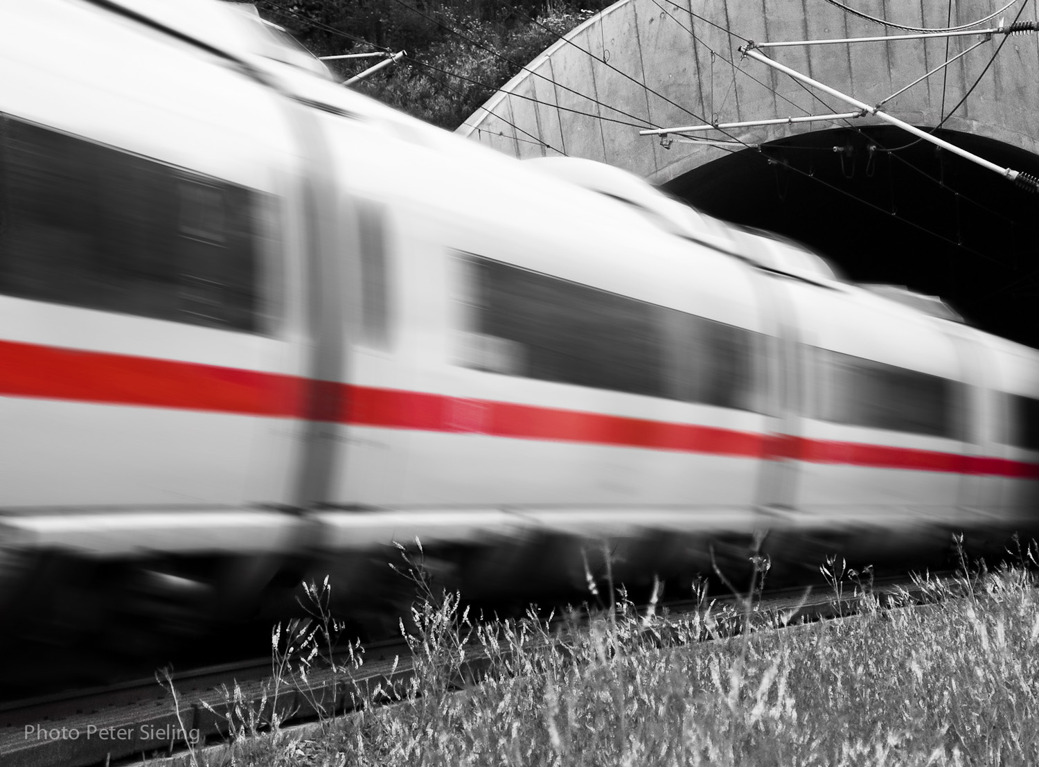 black and white pograph of train speeding under tunnel