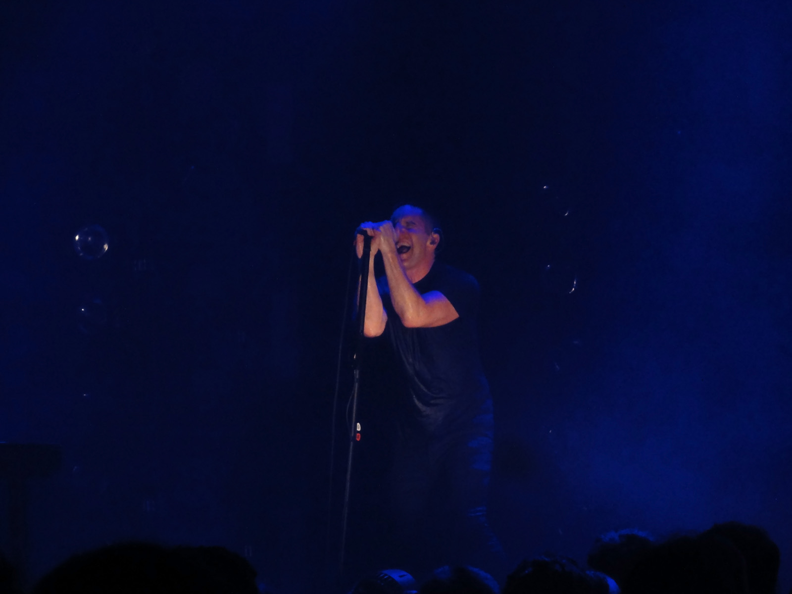 the singer is singing in front of a blue crowd