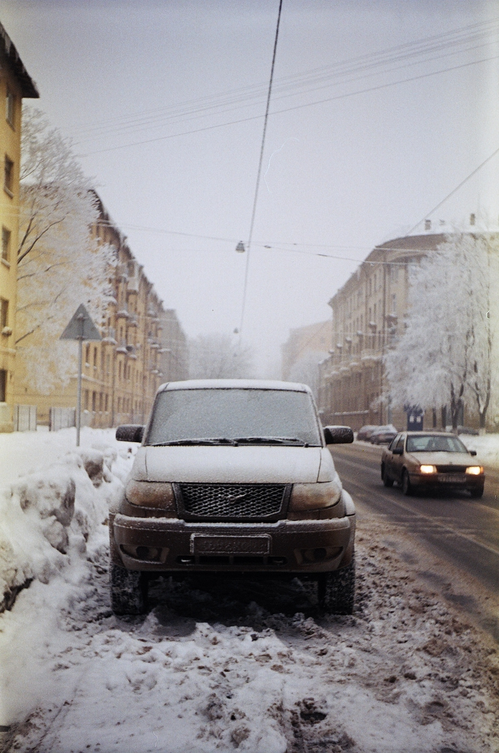 the car is parked in the snow near a street