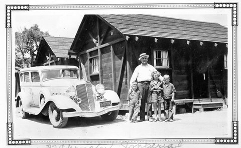 a family poses next to an old car at a ranch