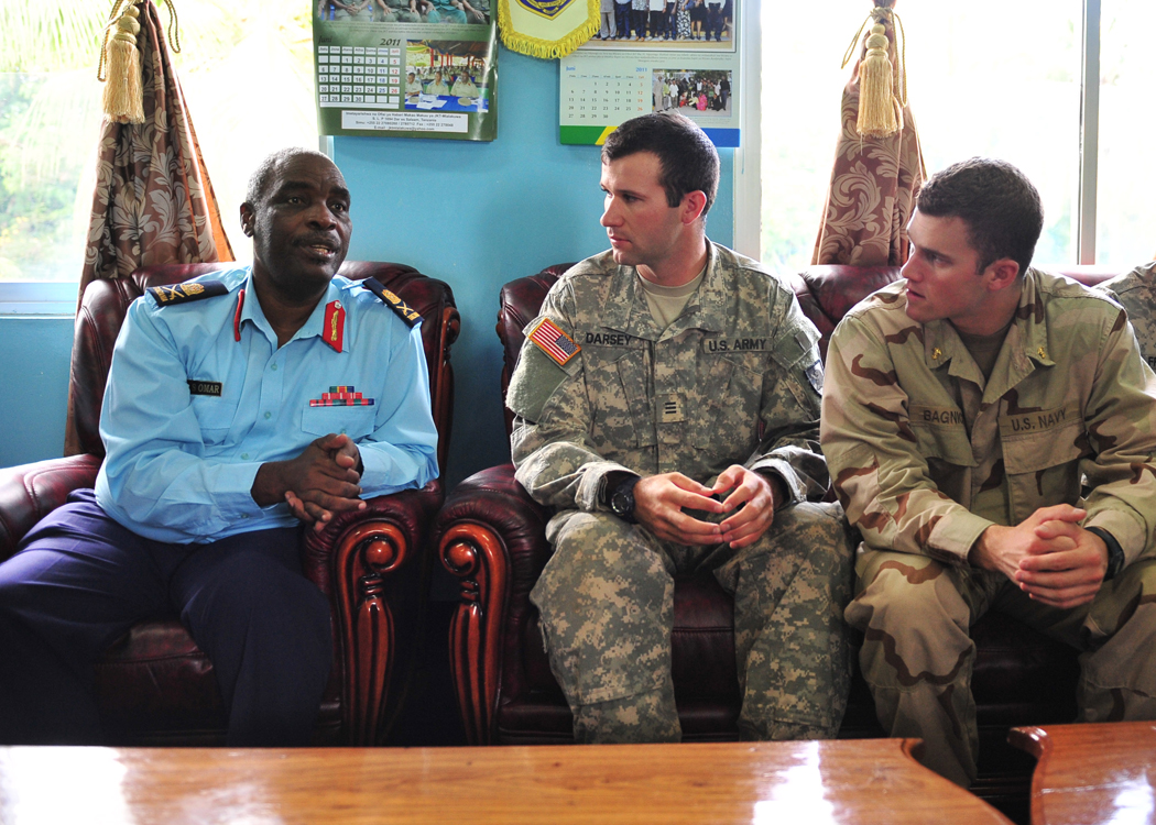 two military men and one is sitting in a room