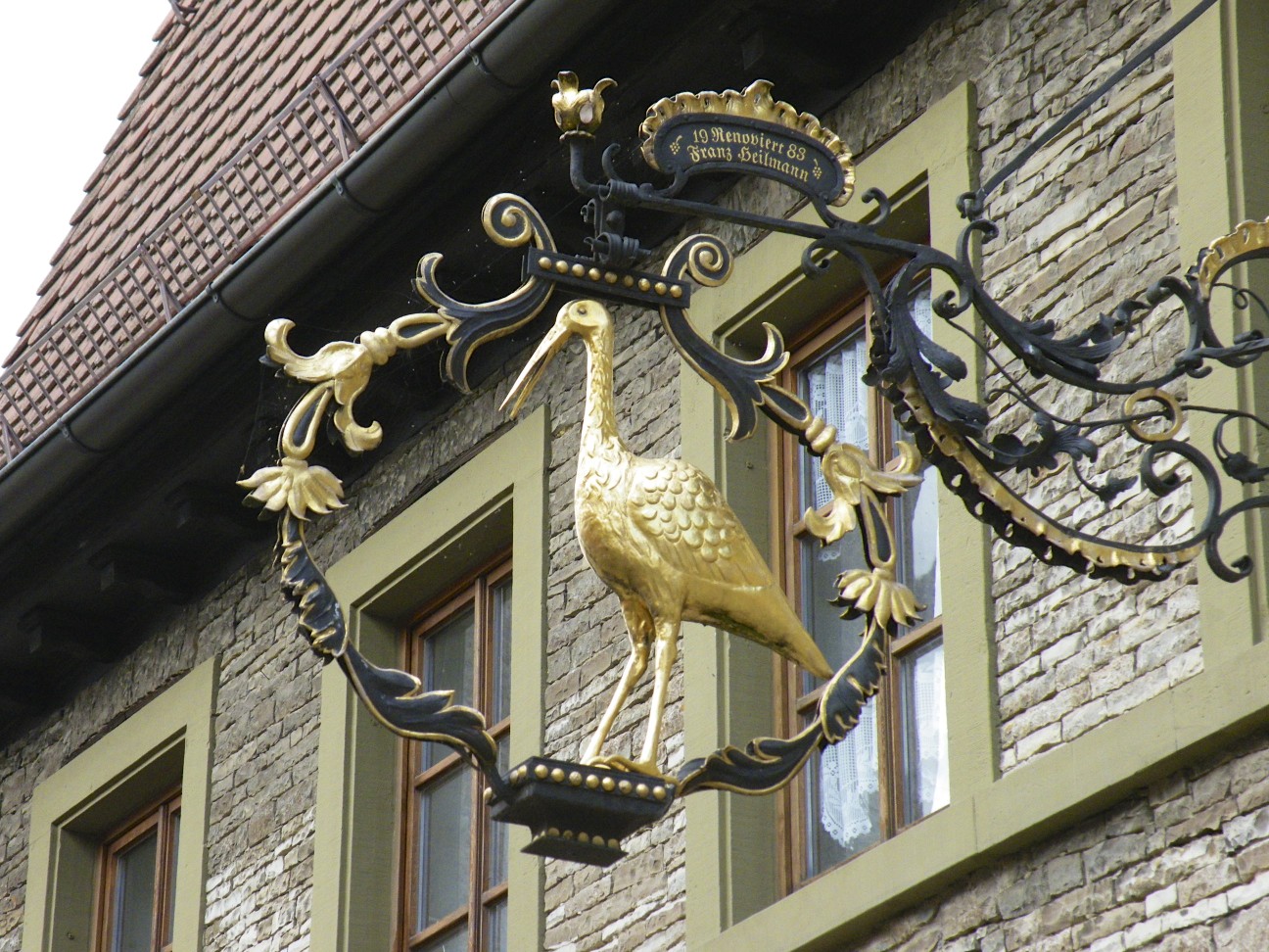 a decorative bird hanging from the front of a building