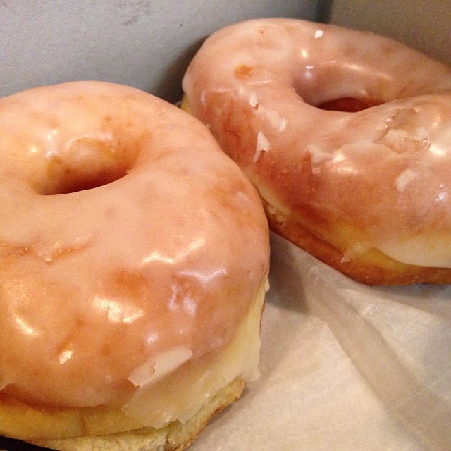 two glazed donuts on top of a brown paper