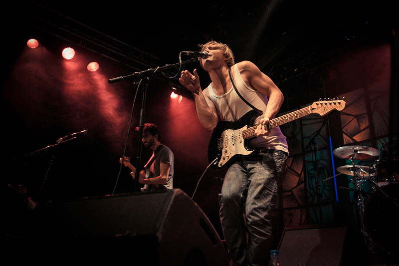 two guys are singing and playing their guitars on stage