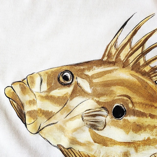 a painting of a fish sitting on top of a white bed sheet