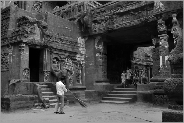 a man is cleaning the ground in front of an old building