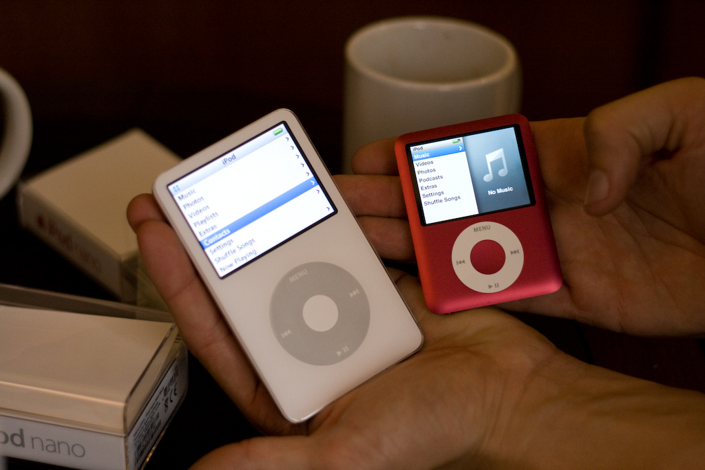 someone holding a colorful ipod and a white and black ipod
