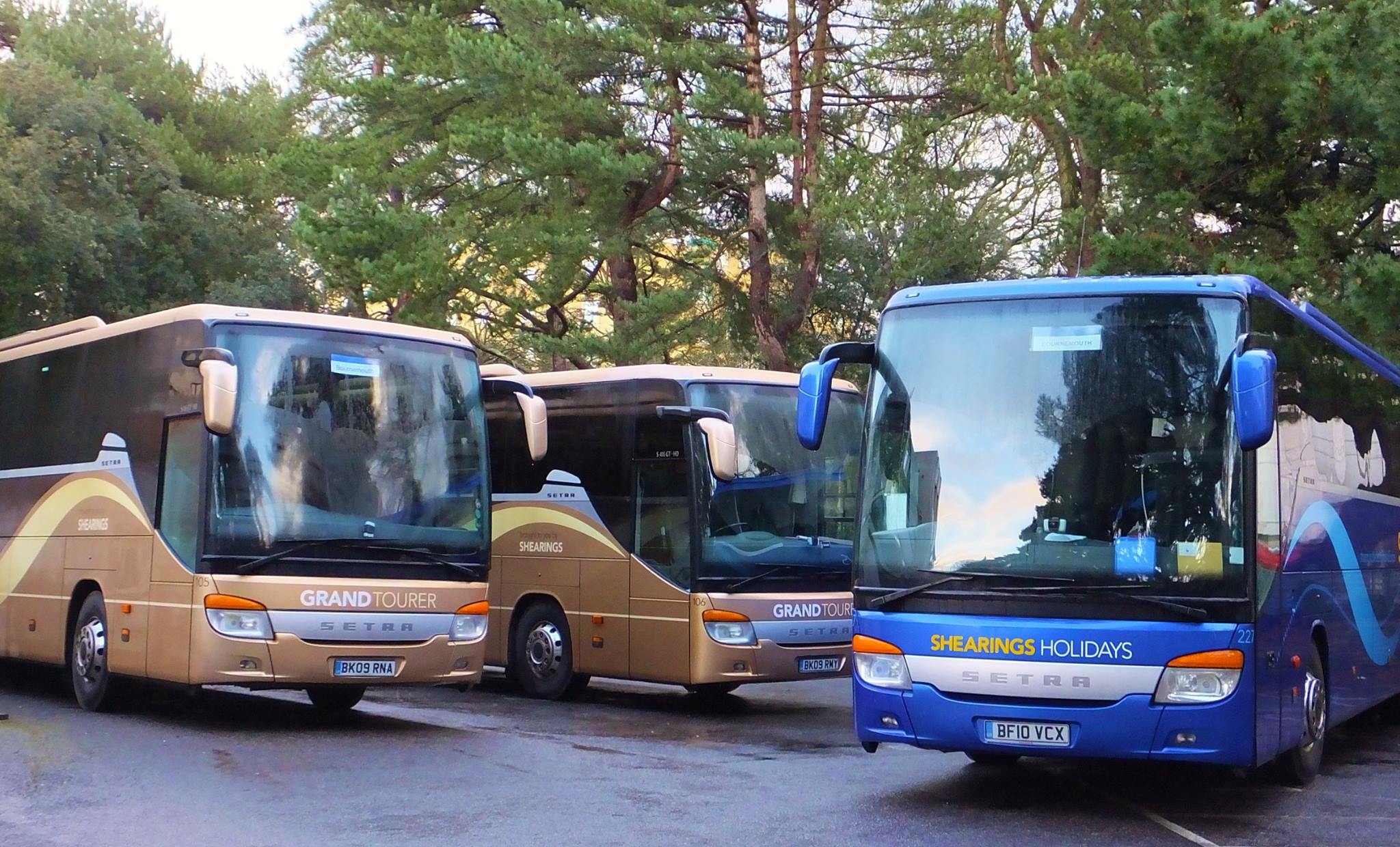 a group of four buses parked together in a parking lot