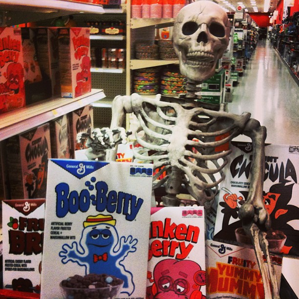 a skeleton with fake bones holding posters in a store