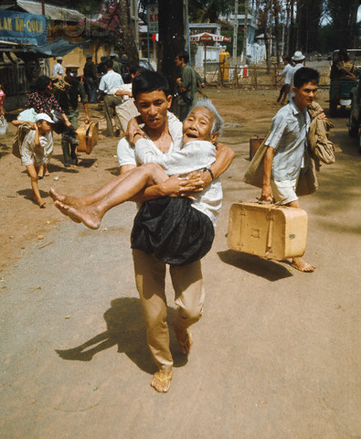 an asian family carries their child over the street