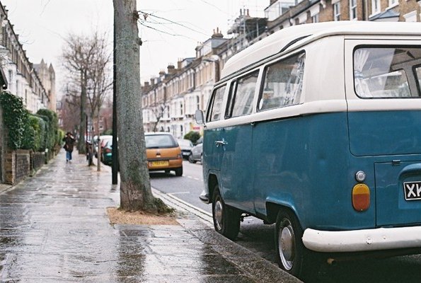 an old style van parked along a curb on a rainy day