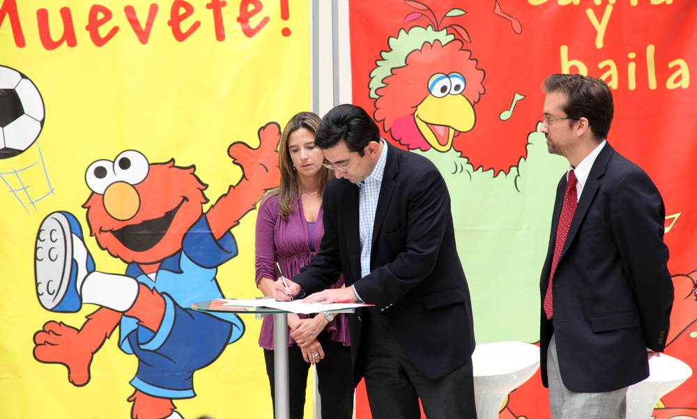 a group of people holding an autographed paper in front of the sesame street mural