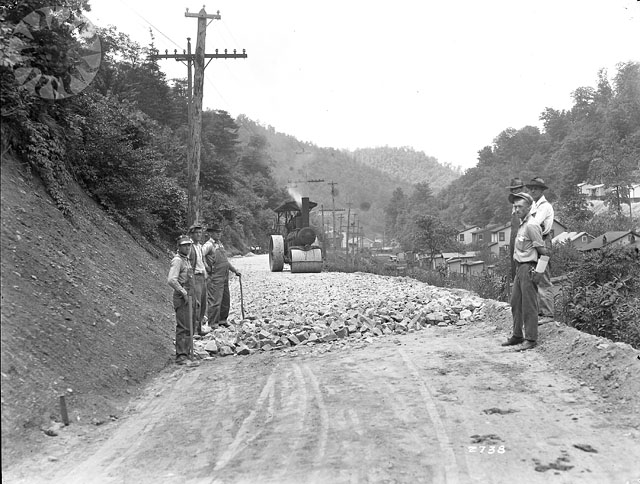 two men standing on a dirt road near a train